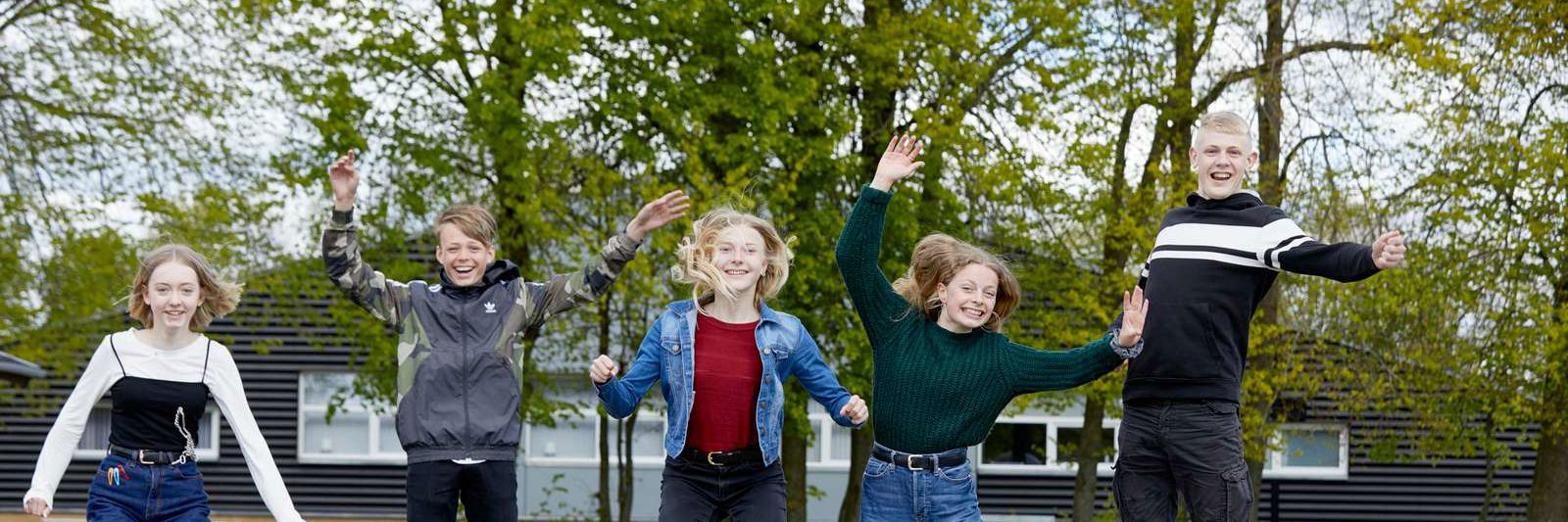 Elever hopper op i luften i skolegården