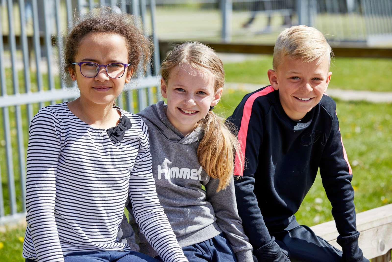 Tre børn sidder i skolegård