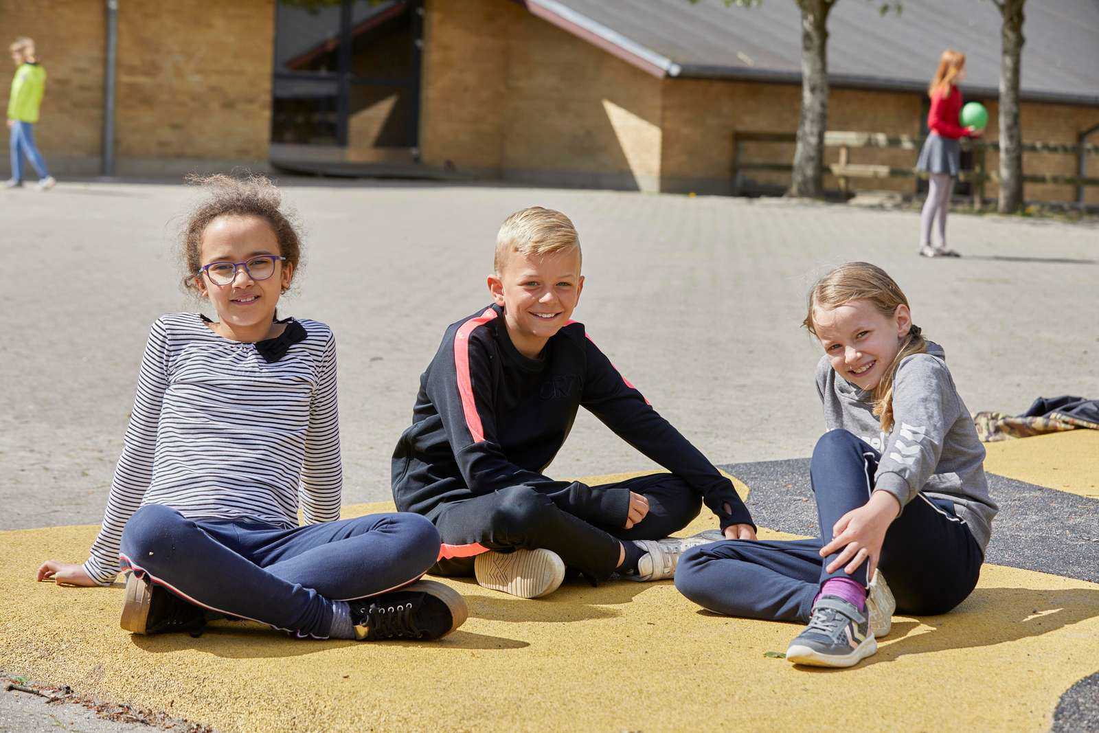 Elever sidder i skolegård