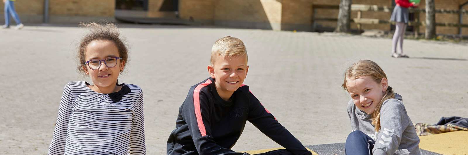 Elever sidder i skolegård