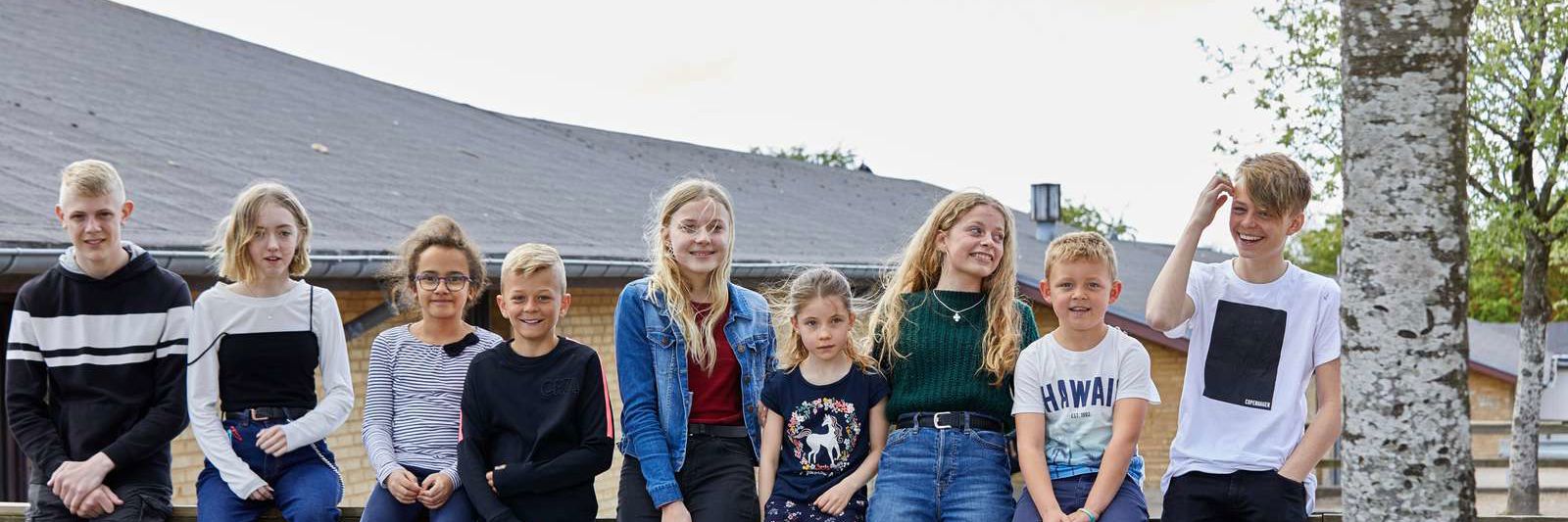 Elever sidder foran skole