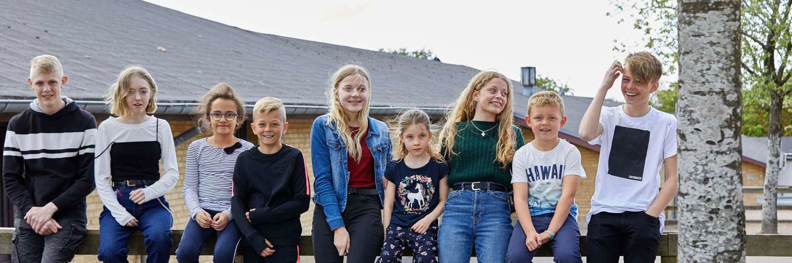 Elever sidder foran skole